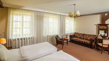Ein Hotelzimmer mit zwei Betten, einem Sofa, einem Schreibtisch und einem Stuhl.
