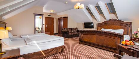 A hotel room with a large bed, a desk with a lamp, a chair, a television mounted on the wall, and a patterned carpet.