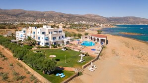 Un hotel frente al mar con varias construcciones, piscina y playa.