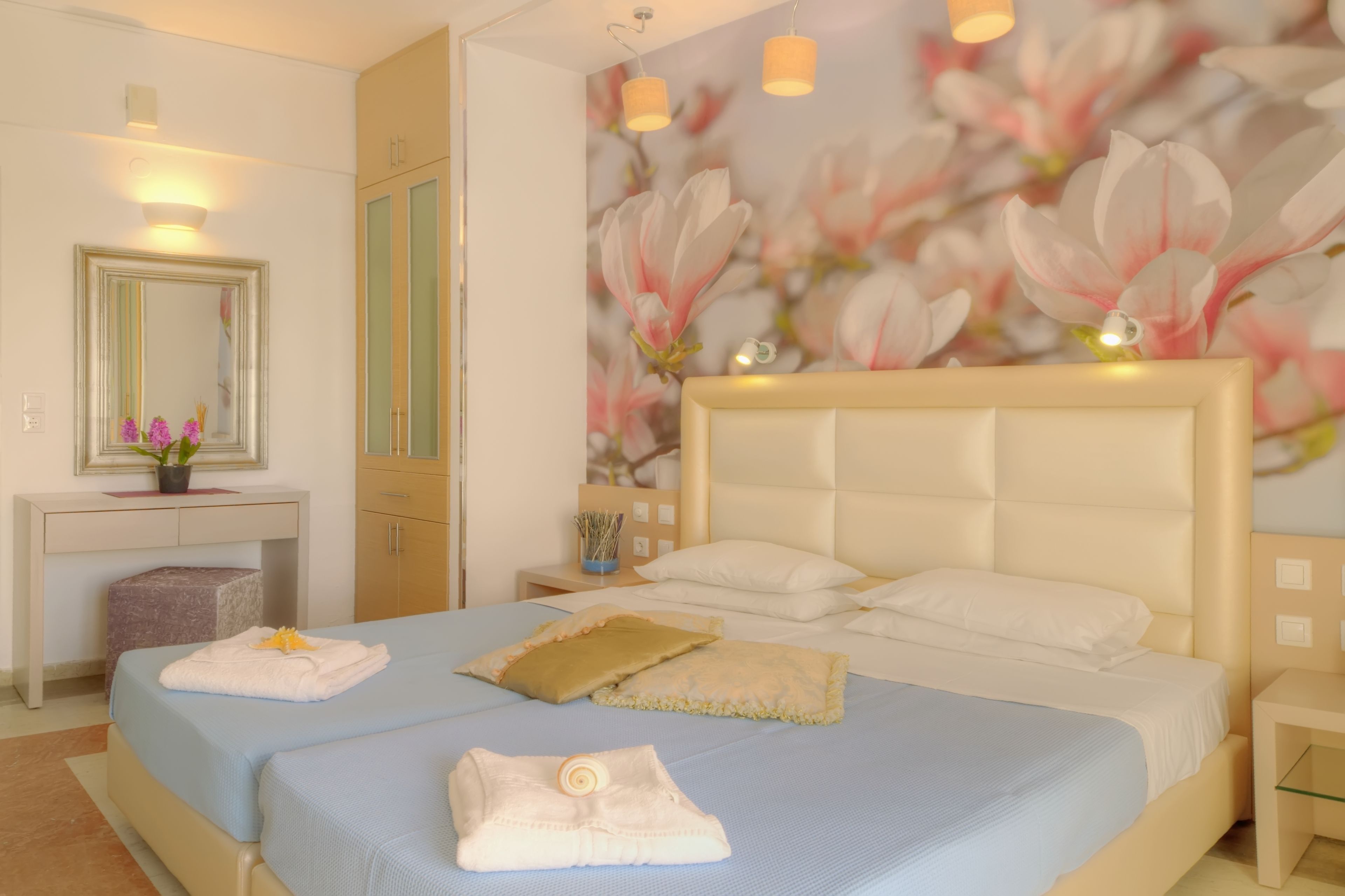 Un dormitorio con una cama grande, una mesita de noche, un aparador, un espejo y una pared con un mural floral.