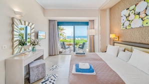 Habitación de hotel con cama, escritorio, silla, un espejo grande y vista al océano.