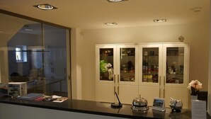 A reception area with a counter, a glass door, and a cabinet with glass doors containing various items.