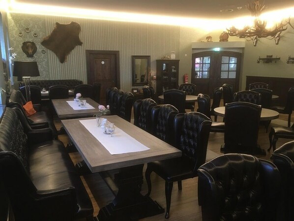 Un restaurante con cabinas y mesas de cuero, una cabeza de animal montada en la pared y un candelabro.