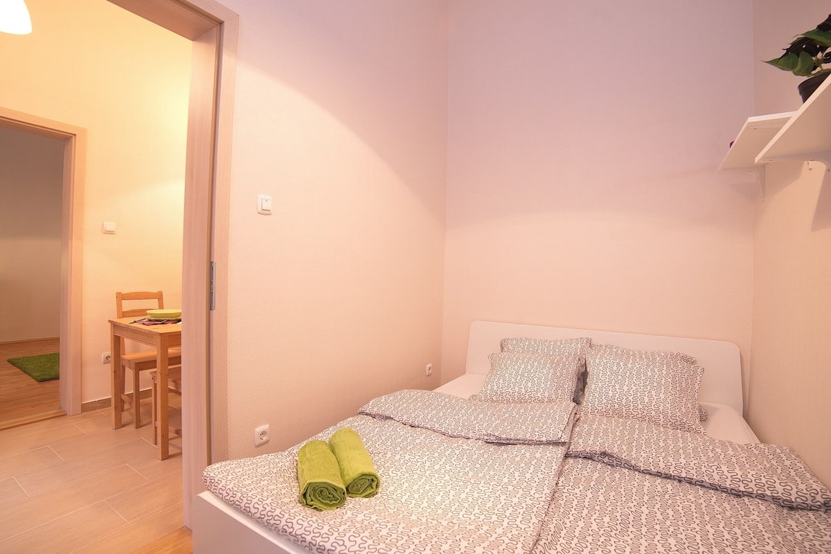 Un dormitorio con cama, almohadas y un par de toallas verdes.
