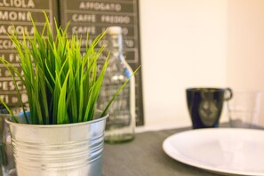 Een metalen emmer met groen gras, een fles en een bord op een tafel.