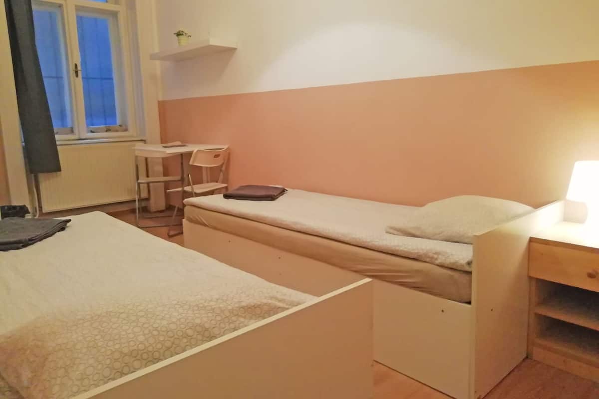 Una habitación pequeña y sencilla con dos camas, un escritorio y una silla.