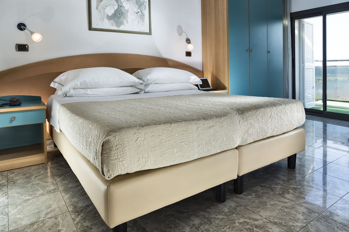 Un dormitorio moderno con una cama grande, una mesita de noche, un armario y un cuadro en la pared.