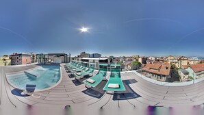 A rooftop swimming pool with lounge chairs and a sun deck, overlooking a cityscape. - Milano Resort (Bellaria-Igea Marina)