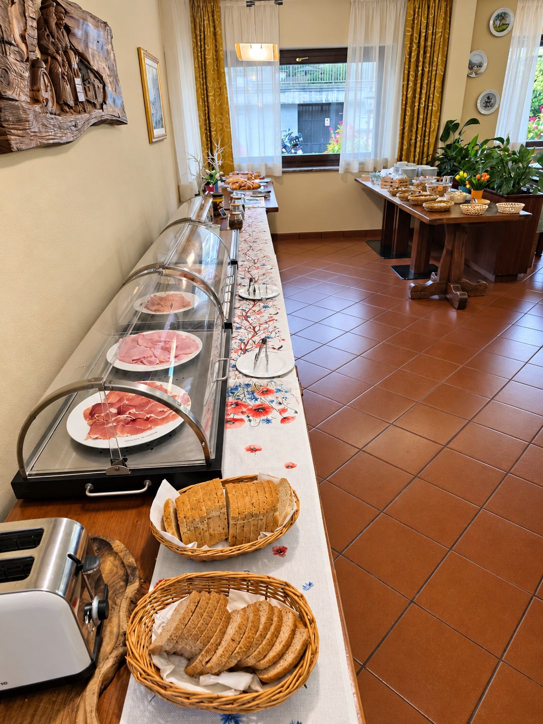 Montaje de bufé con diversos alimentos, una exhibición de pan y un elemento decorativo en la pared.