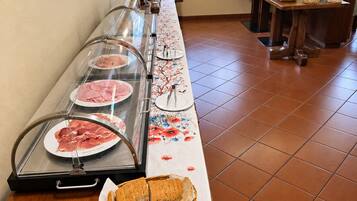 Montaje de bufé con diversos alimentos, una exhibición de pan y un elemento decorativo en la pared.