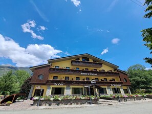 Un hotel con fachada amarilla, balcones con jardineras florales y un letrero que dice 'Comtes de Chaltant Hotel'.