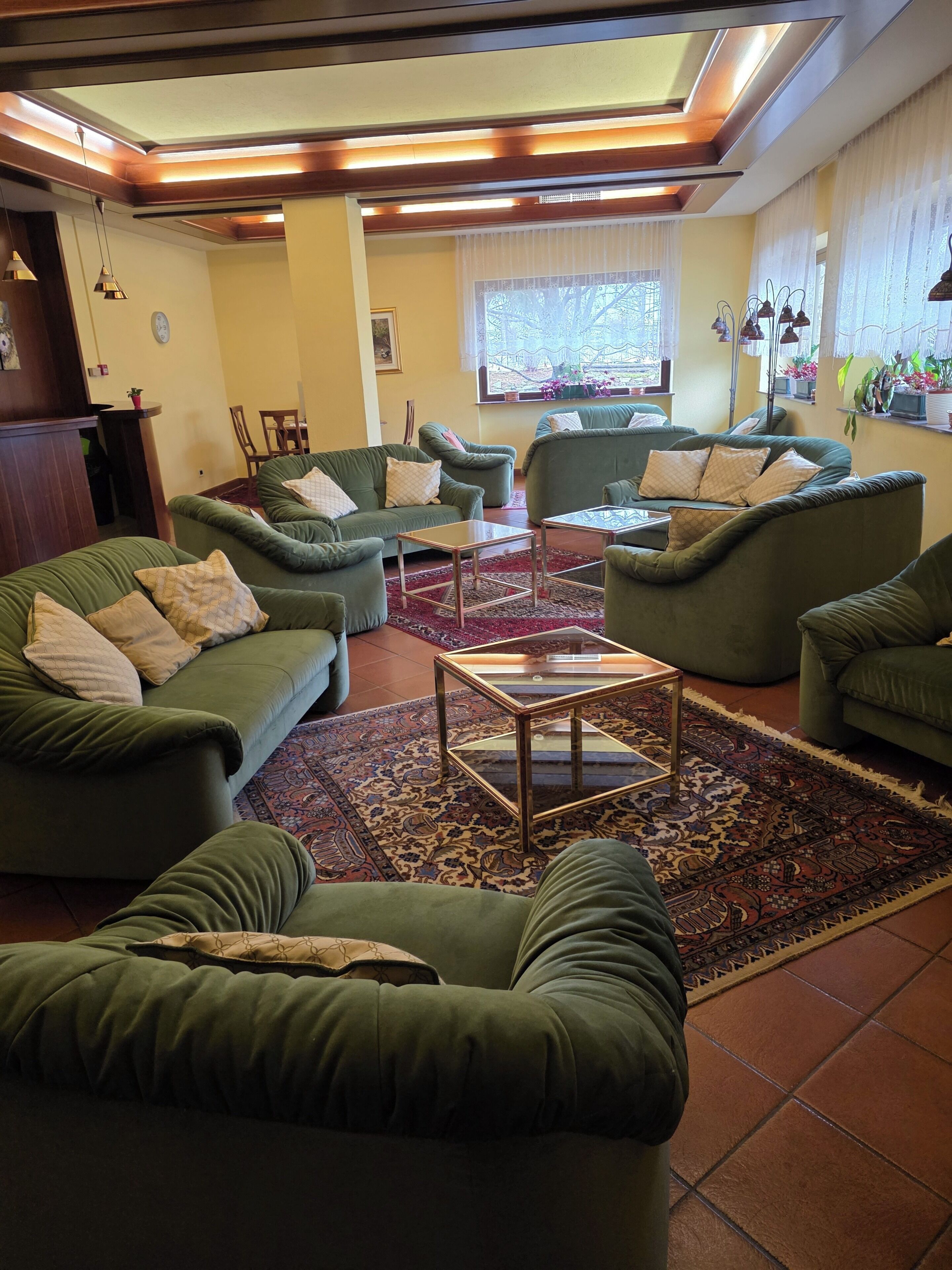A living room with green sofas, a glass coffee table, and a patterned rug.