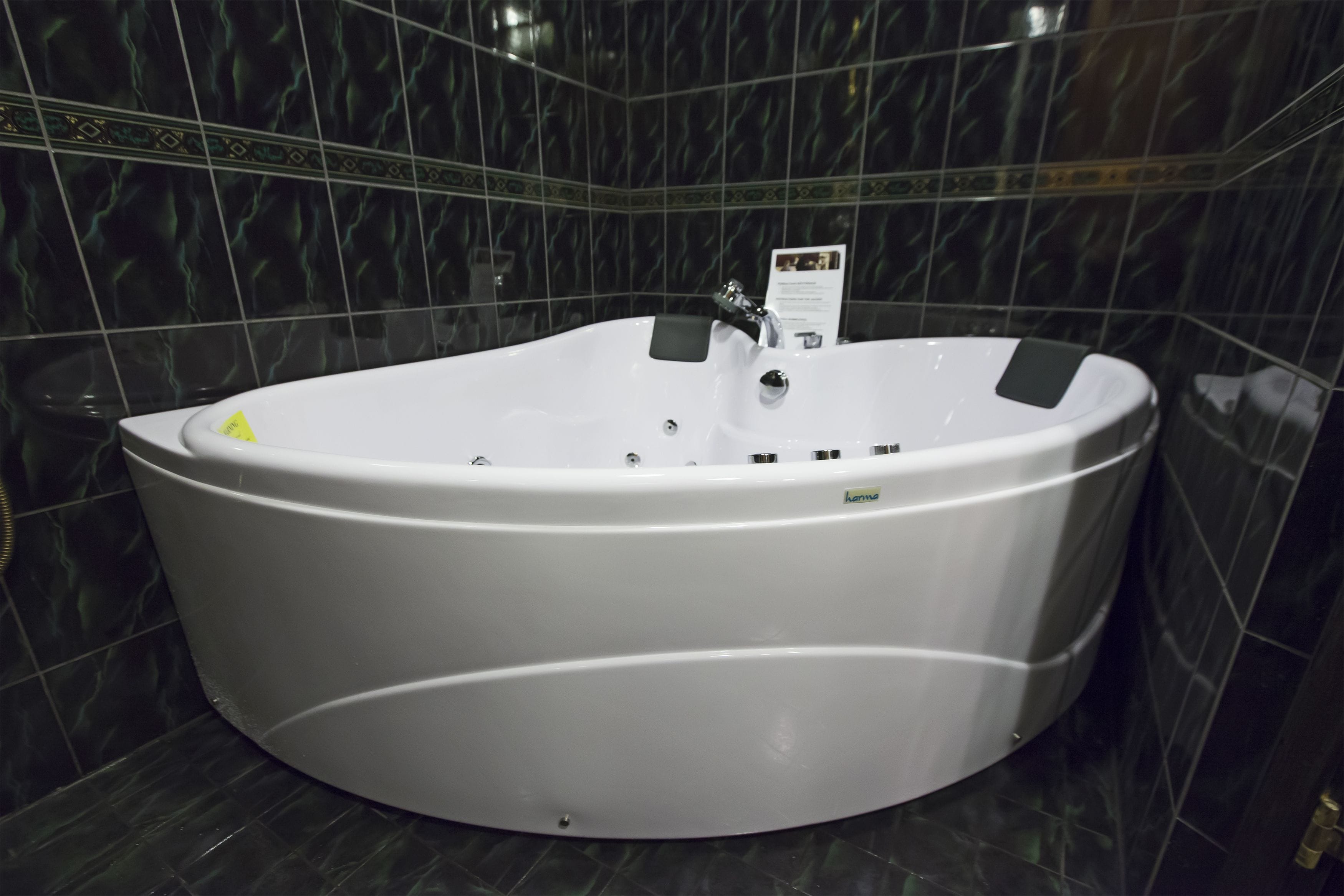 Une grande baignoire blanche, autoportante, dans une salle de bain aux carreaux foncés et à motifs.