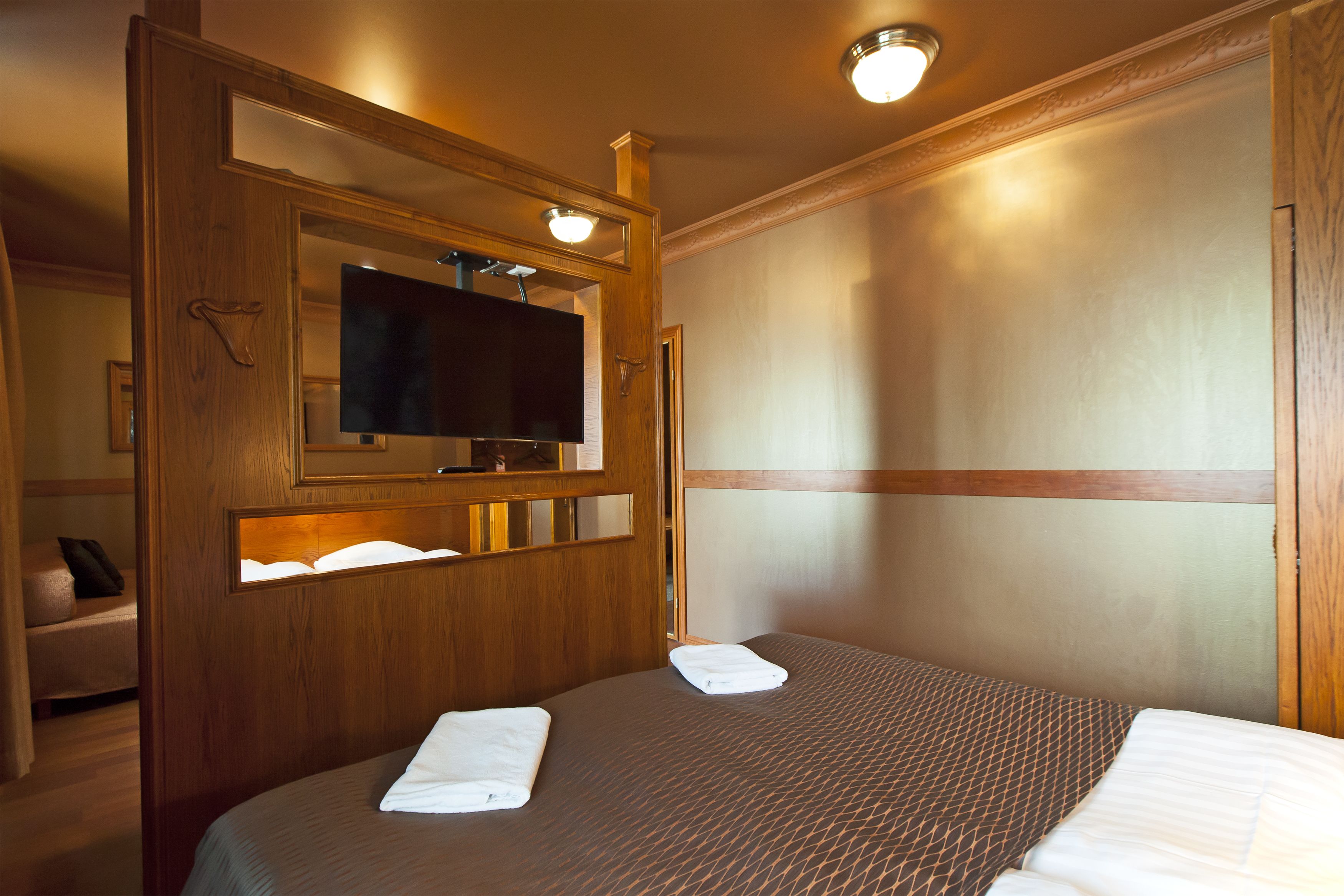 Ein Hotelzimmer mit einem Bett, einem Fernseher und einer Holzwand.
