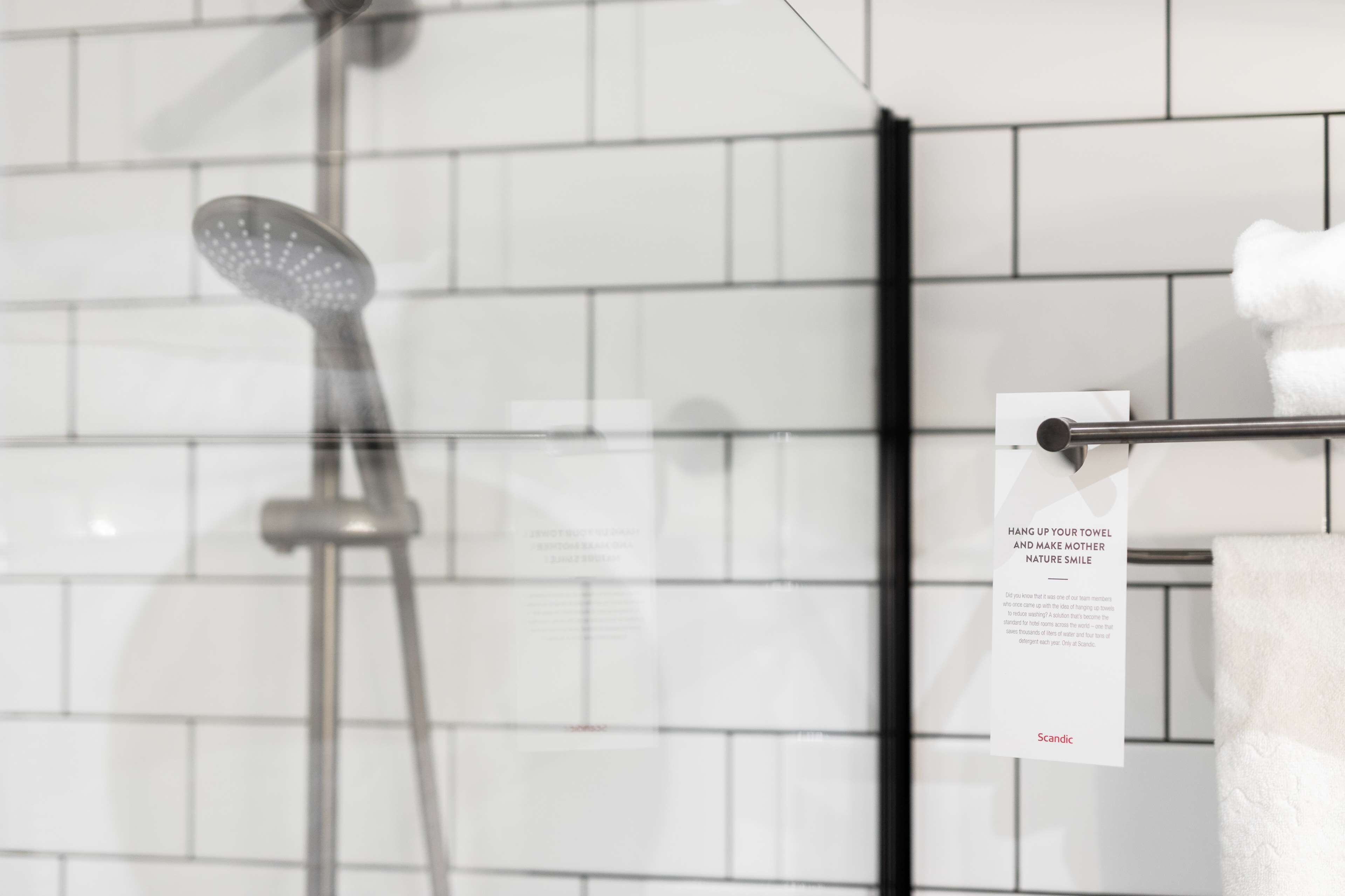 A bathroom with a shower, a towel rack, and a sign.