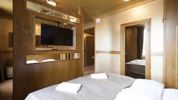 Een hotelkamer met een groot bed, een televisie, een houten kledingkast en een spiegel.