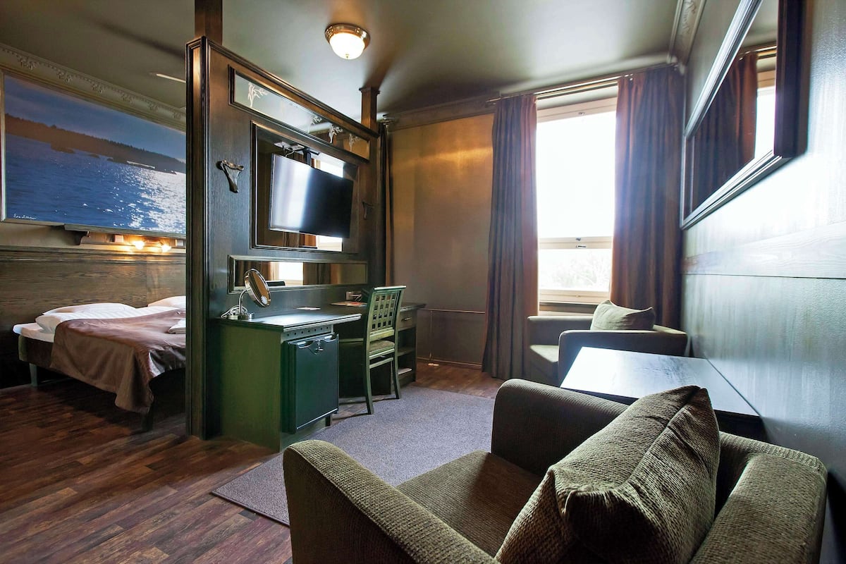 Una habitación de hotel pequeña con cama, escritorio, silla y televisor.
