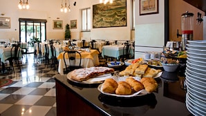 Un comedor con varias mesas, un bufé de pasteles y pan, y un cuadro en la pared.