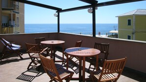 Un balcón con mobiliario de madera y vista al mar.