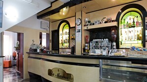 Una zona de bar con mostrador, estanterías llenas de botellas, un reloj y un letrero que dice "La Marina".