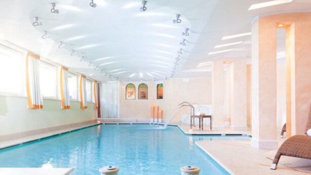 Une piscine intérieure à l’eau claire, dotée d’un sol carrelé et d’un plafond pourvu d’un éclairage encastré.