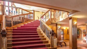 Una gran escalera con alfombra roja que conduce a un área de recepción, con un letrero que dice "Hotel Splendid".
