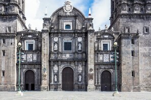 Un edificio histórico con arquitectura ornamentada, que presenta grandes puertas arqueadas y estatuas.