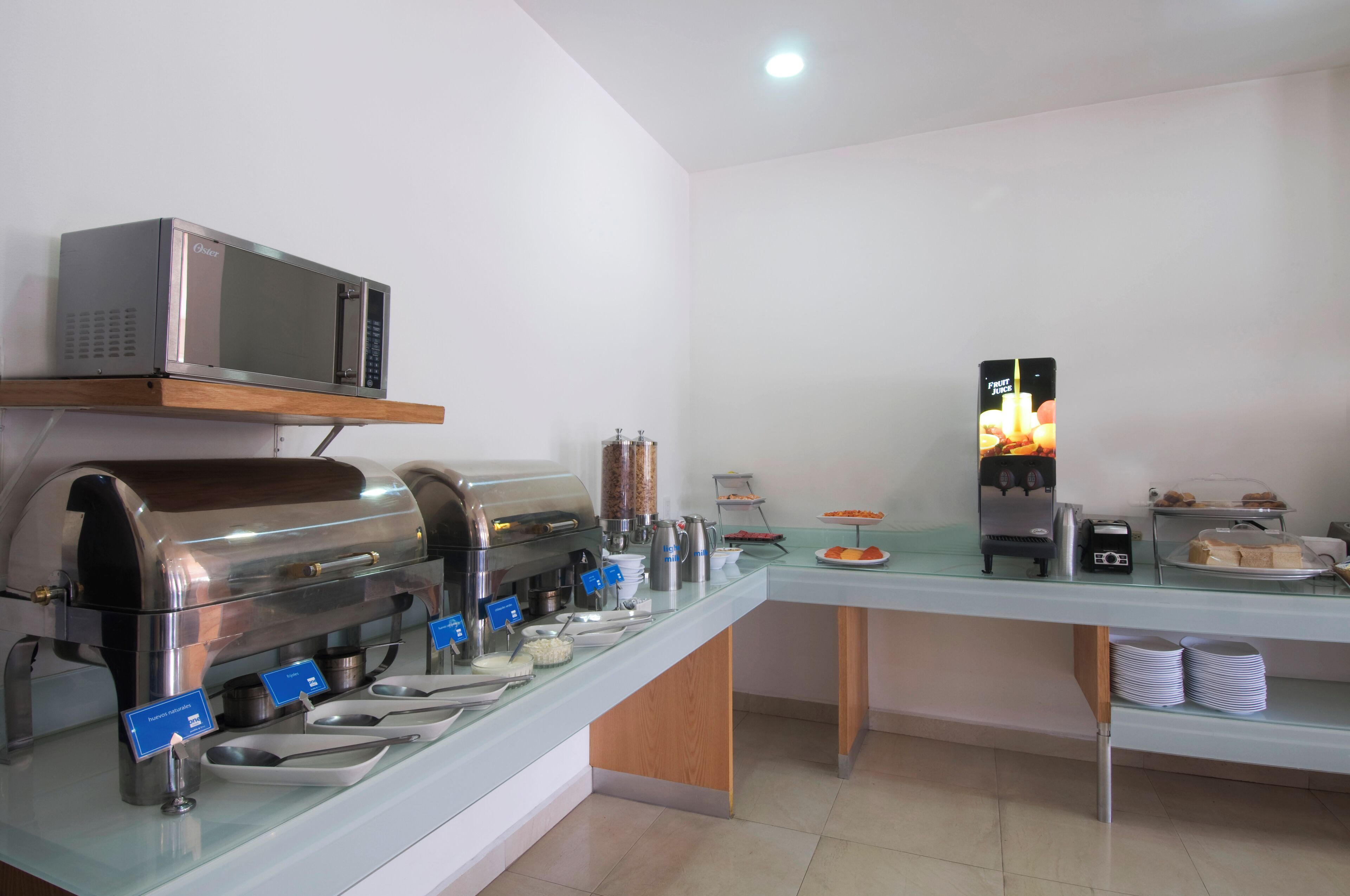 A buffet setup with a microwave, coffee machine, and a beverage dispenser.