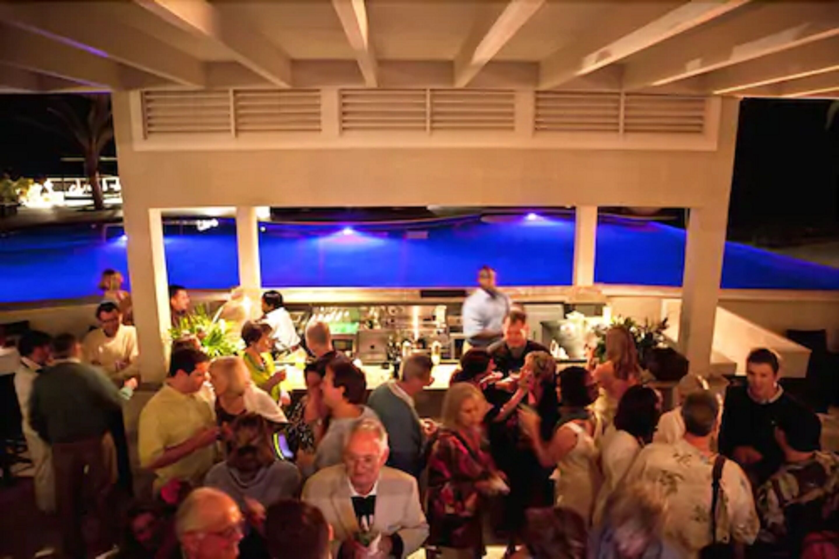 A crowded indoor space with a pool area in the background.