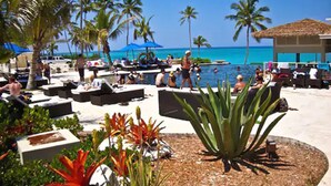 A resort pool area with lounge chairs, palm trees, and a view of the ocean. - Sky Beach Club (Governor's Harbour)