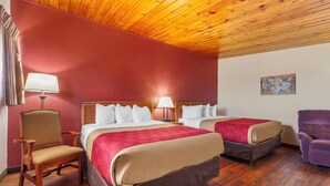 A hotel room with two beds, wooden flooring, a wooden ceiling, and a red wall.