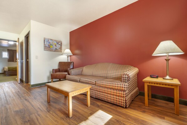 A living room with a plaid sofa, a wooden coffee table, a lamp, and a painting on the wall.