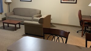 A living room with a sofa, a coffee table, a dining table with chairs, and two framed pictures on the wall.