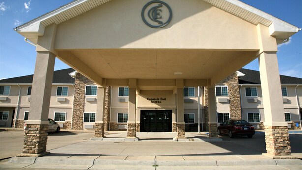 A hotel entrance with a beige facade, stone pillars, and a clear blue sky.