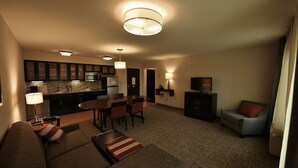 A modern living room with a sofa, a dining table, and chairs. There is a kitchen area with cabinets and a microwave. - Staybridge Suites Liverpool Syracuse by IHG (Liverpool)