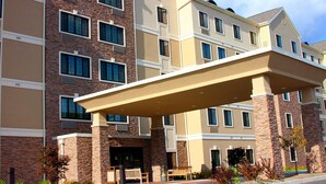 Ein mehrstöckiges Hotel mit überdachter Eingangspforte und einer Ziegelaußenwand.
