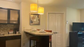 A compact kitchen with a bar area, a dining table, and a television.