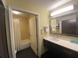 A bathroom with a bathtub, a sink, a mirror, and a shower curtain.