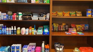 Ein übersichtlicher Laden mit Regalen, gefüllt mit verschiedenen Haushalts- und Körperpflegeprodukten, darunter Reinigungsmittel, Toilettenartikel und Snacks.