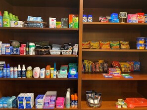 Un magasin bien organisé, avec des étagères remplies de divers produits d’entretien ménager et de soins personnels, notamment des produits de nettoyage, des articles de toilette et des en-cas.