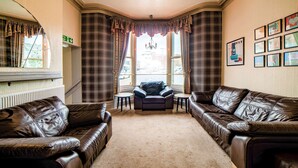 A living room with two leather sofas, a small armchair, and a chandelier. - Comfort Inn Blackpool Gresham (Blackpool)