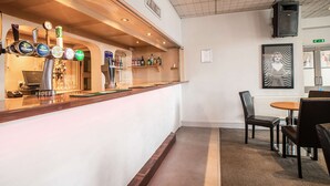 A bar area with multiple beer taps, a counter, and a seating area with chairs and a table. - Comfort Inn Blackpool Gresham (Blackpool)
