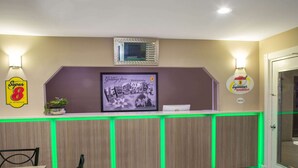 A restaurant with a wooden counter, green neon lights, a framed menu, and a Super 8 sign.