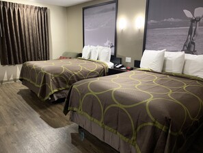 A hotel room with two beds, a desk, a telephone, and a wall with a picture.