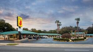 A motel with a green roof, a parking lot, and a sign for Super 8 by Wyndham.