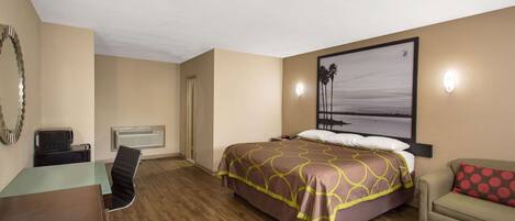 A hotel room with a bed, a desk, a chair, a sofa, and a painting on the wall.