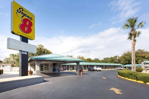 A motel with a large 'Super 8' sign, a covered parking area, and a row of rooms with a green roof. - Super 8 by Wyndham Pensacola NAS Area (Pensacola)