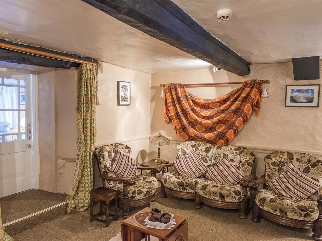 A cozy living room with floral-patterned sofas, a small table, and a hanging blanket.