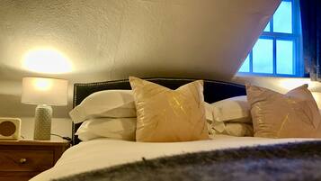 A bedroom with a bed, pillows, a bedside lamp, and a window.