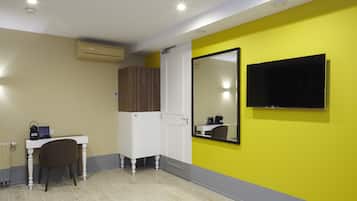 Quarto com escrivaninha, cadeira, guarda-roupa, espelho e televisão.